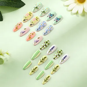 Detailed view of almond-shaped press-on nails with green floral and butterfly patterns