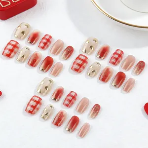Short square press-on nails with red heart patterns and golden French cat-eye design