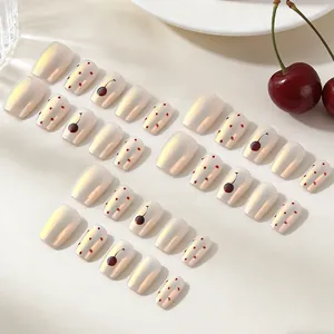 Short pearlescent almond press-on nails with red cherry pattern and dotted art