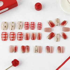 Short square press-on nails with red plaid, golden hearts, and cat-eye gradient finish