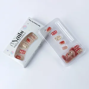 Detail of short square press-on nails set with gold heart accents and red plaid patterns