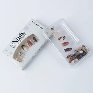 Detail of press-on nails set with red cherry and gold patterns in white display box