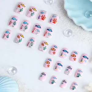 Macro detail of ocean-themed press-on nails with fish and coral patterns on pink base