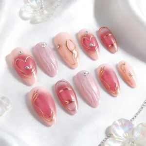 Pink gradient almond press-on nails with golden heart lines and rhinestone accents