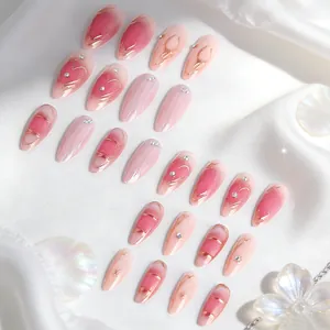 Close-up of pink gradient press-on nails with gold lines and sparkling rhinestones