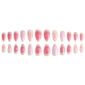 Pink gradient almond press-on nails with gold edges and tiny heart rhinestone details