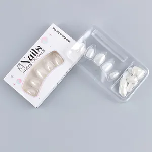 Detail view of pearlescent white press-on nails in an almond shape with premium packaging