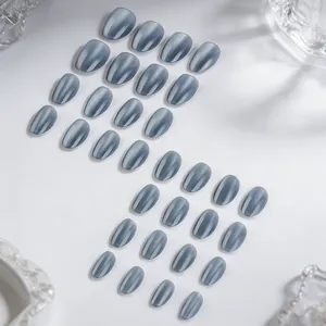 Gros plan sur des faux ongles œil-de-chat bleu brumeux avec pointes ovales brillantes