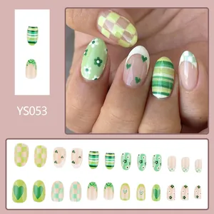 Green oval press-on nails set with heart, floral, and checkered stripe patterns