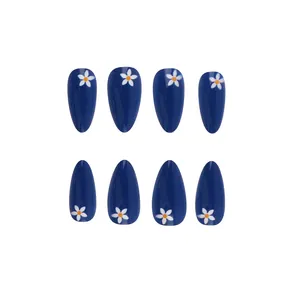 Close-up of blue glossy press-on nails featuring white daisy patterns on almond shape