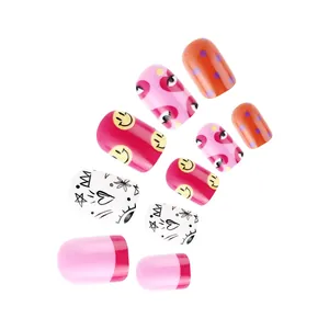 Detail of short round glossy press-on nails with colorful smiley face and heart designs