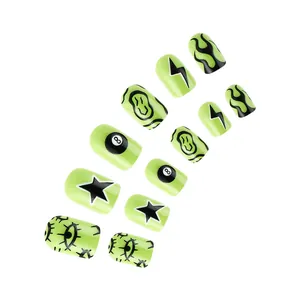 Detail of neon green Halloween press-on nails with black 8-ball and graffiti patterns