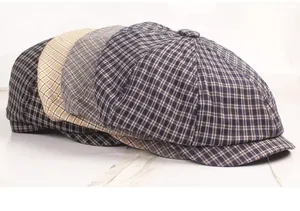 Detailed close-up of four newsboy caps in navy, grey, beige, and monochrome plaid patterns