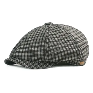Detail of classic plaid newsboy cap with textured gray houndstooth fabric and side leather label