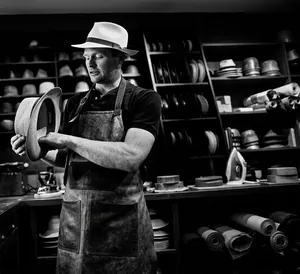Primo piano di un artigiano che realizza un cappello fedora vintage in lana a quadri