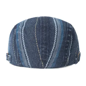 Detail view of denim flat cap with vertical stripe patterns and metal side buckles