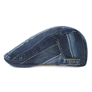 Detailed side view of washed denim flat cap with vintage bronze buckle and stripe accents