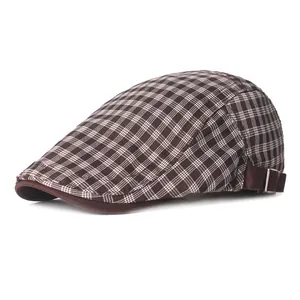 Detailed view of the brown plaid beret featuring an adjustable side buckle and fabric texture