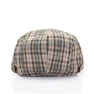 Classic British plaid beret flat cap with vintage bronze buckles on a white background