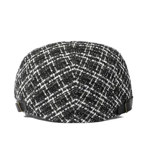 Détail de la lanière en cuir réglable et boucle en métal bronze sur la casquette en tweed