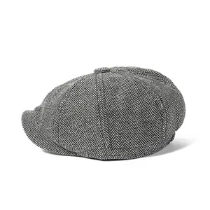 Detailed view of the herringbone wool texture and top button on a gray newsboy cap