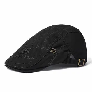 Détail du béret en coton noir avec broderie de marque et boucle en métal ajustable