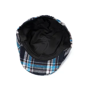Detail of plaid newsboy cap showing blue tartan fabric and black inner lining texture
