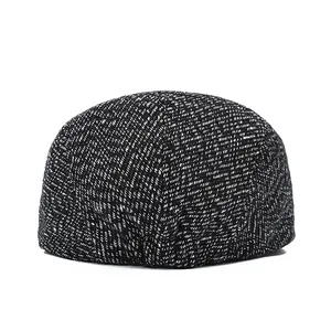 Close-up of thick winter newsboy cap with black and white tweed herringbone texture