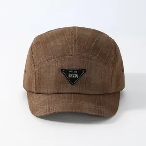Detail of dark brown five-panel camping cap with grid texture and triangle logo patch