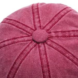 Macro shot of burgundy washed cotton newsboy cap top with stitched seams and central button
