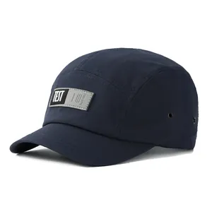 Casquette 5-panel bleu marine à visière courte avec étiquette tissée sur fond blanc neutre