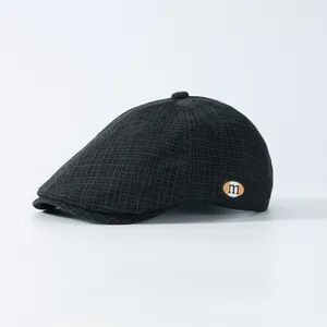 Gros plan sur une casquette vintage grise à carreaux avec petit patch décoratif lettre m