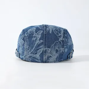 Blaue Denim-Schirmmütze mit Blumenmuster und Metallschnallen auf weißem Hintergrund