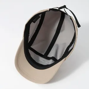 Détail de la casquette beige à 5 panneaux montrant les coutures internes et la doublure