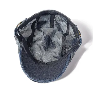 Detail view of washed denim flat cap interior with 100% cotton label and metal buckle