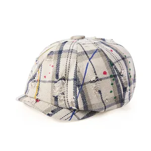 Détail de la casquette gavroche à carreaux avec taches de couleur et trous vintage