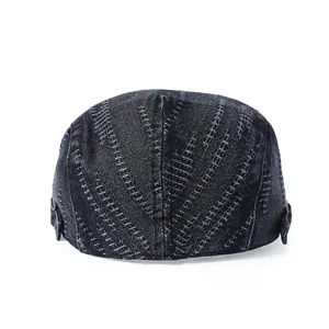 Détail d'une casquette gavroche en jean foncé avec coutures blanches et boucle en métal