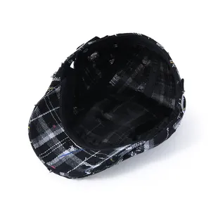 Detail view of cotton plaid newsboy hat interior with washing label and distressed edges