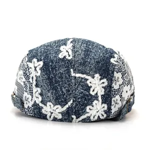 Détail de la broderie en dentelle florale et boucle métallique sur le béret denim