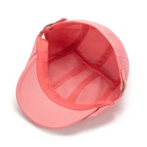 Détail de la casquette rose en coton montrant les coutures intérieures et la boucle en métal