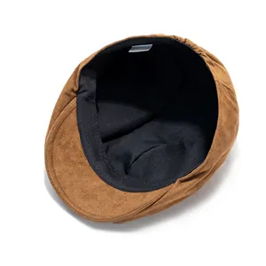 Détail de la casquette plate en daim marron montrant la doublure noire et l'étiquette