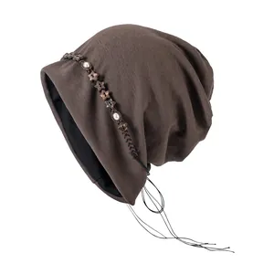Détail du bonnet marron café avec des étoiles en bois et des breloques à pompons