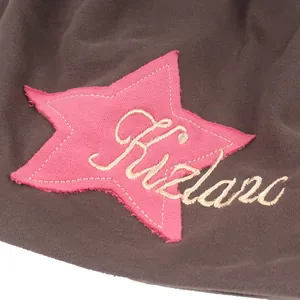 Macro detail of pink star patch with Fizland embroidery on dark knit beanie hat