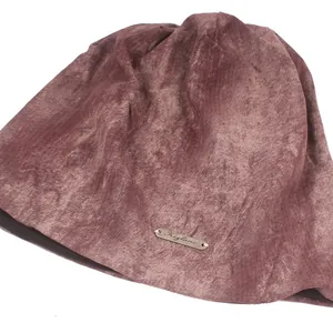 Lichtroze fluwelen slouchy beanie muts met metalen label op een witte achtergrond