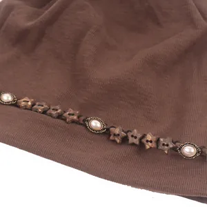 Détail du bonnet en tricot café avec étoiles en bois vintage et charmes de perles