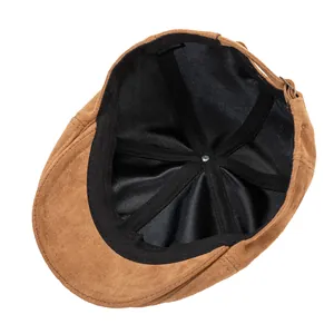 Detail view of brown faux suede beret featuring black lining and adjustable strap