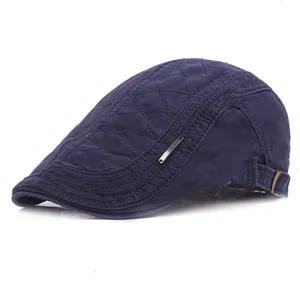 Detail of navy blue quilted beret hat with metal logo and cotton canvas texture
