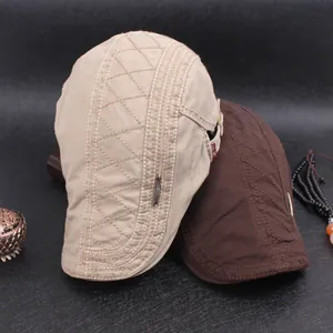 Detail of khaki and brown flat caps with diamond quilted stitching and metal buckles