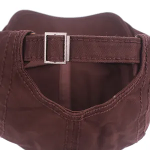Close-up of dark brown cotton flat cap with adjustable metal buckle and twill texture