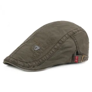 Detail of army green vintage beret cap showing side embroidery and metal badge